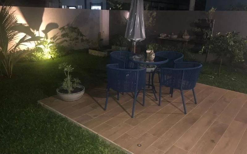 Terraço exterior com assentos azuis e plantas iluminadas.