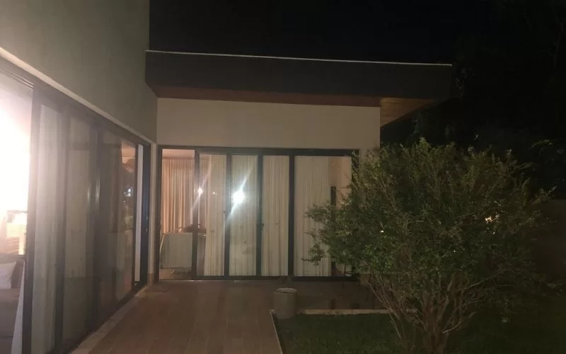 Casa moderna iluminada à noite, jardim à frente.