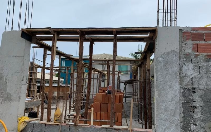 Construção de casa com tijolos e estruturas metálicas.