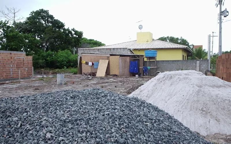 Quintal com materiais de construção e roupa pendurada.