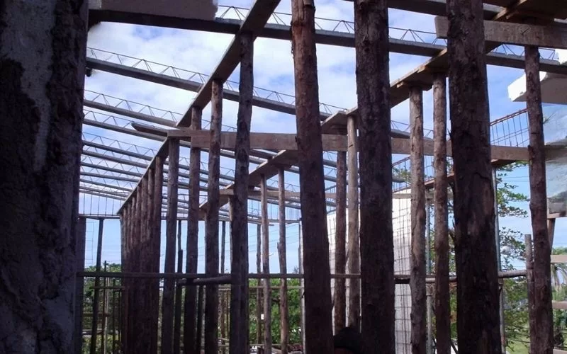 Construção com pilares de madeira e céu azul.
