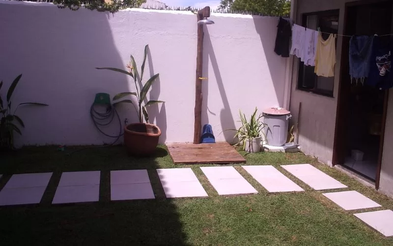 Jardim com duche ao ar livre e roupa a secar.