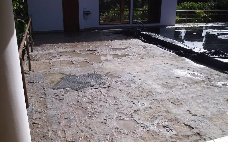 Pátio danificado ao lado de piscina vazia.
