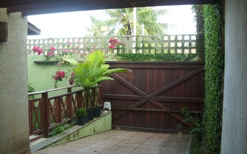 Jardim com portão de madeira e plantas ao redor.