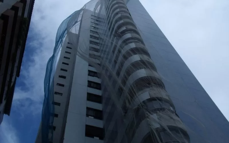 Edifício alto envolto em rede de proteção.