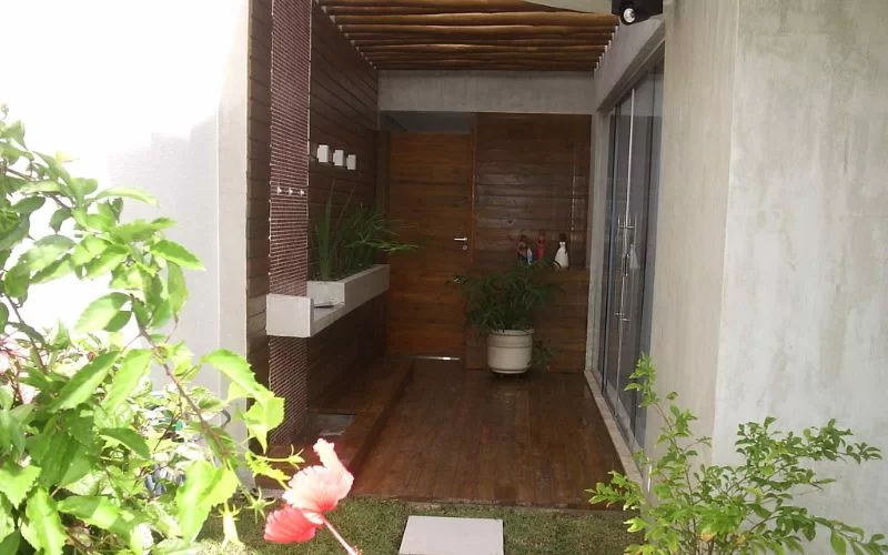 Entrada de casa moderna com plantas e madeira.