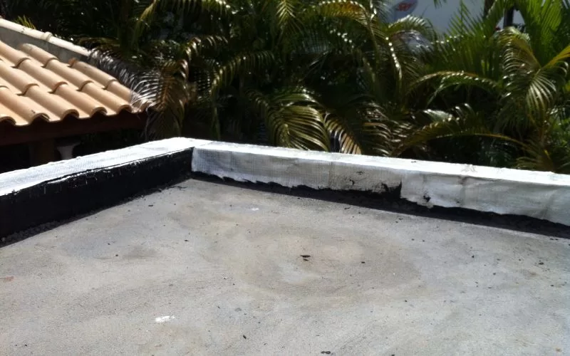 Telhado plano com vegetação ao fundo.