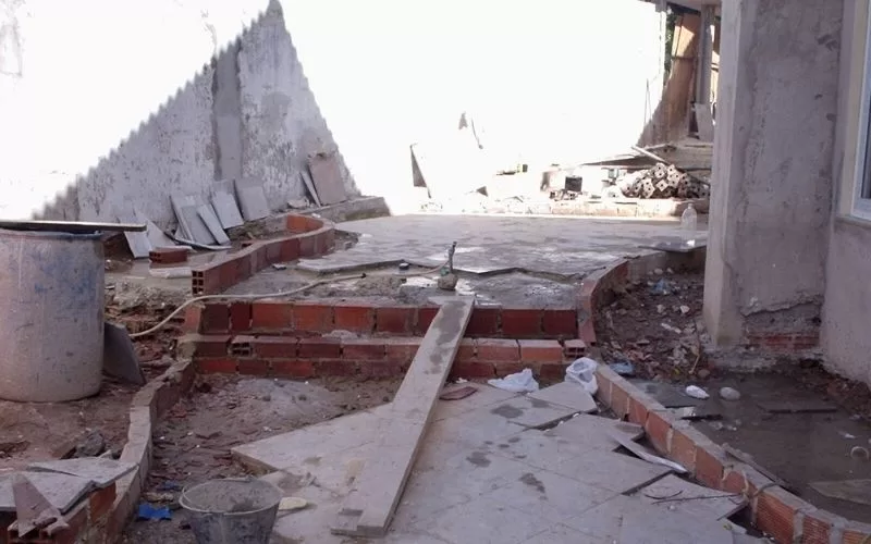 Área de construção com tijolos e materiais diversos.