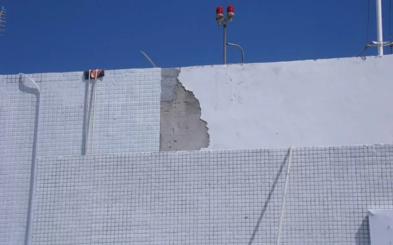 Parede com azulejos danificados e duas antenas.