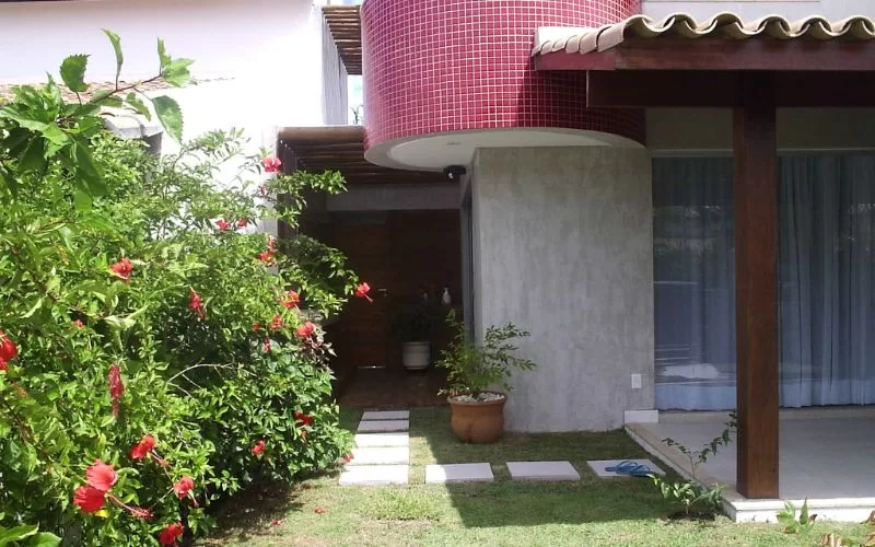 Jardim com hibiscos em frente a casa moderna.