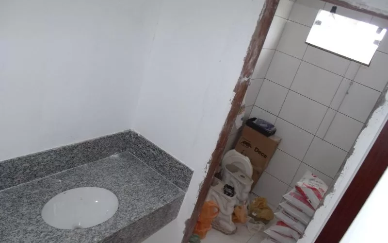 Casa de banho em construção, com materiais no chão.