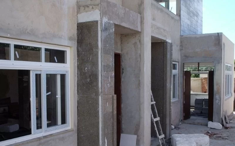 Casa em construção com escadas e janelas visíveis.