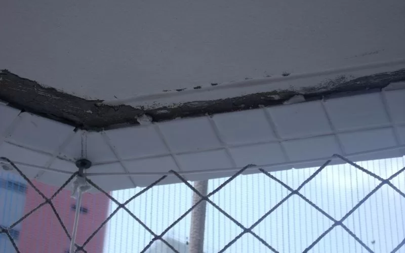 Deterioração no teto com azulejos e rede.