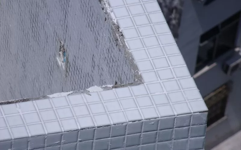 Canto de edifício coberto de azulejos brancos quadrados.