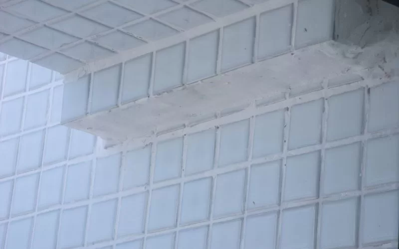 Detalhe de parede revestida com azulejos brancos.