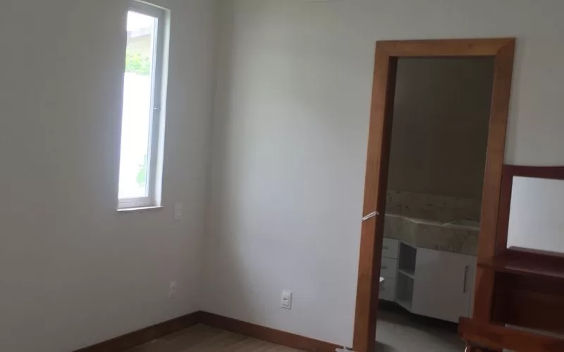 Quarto vazio com janela e porta para casa de banho