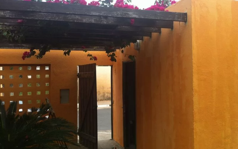 Entrada com paredes amarelas e flores vermelhas.