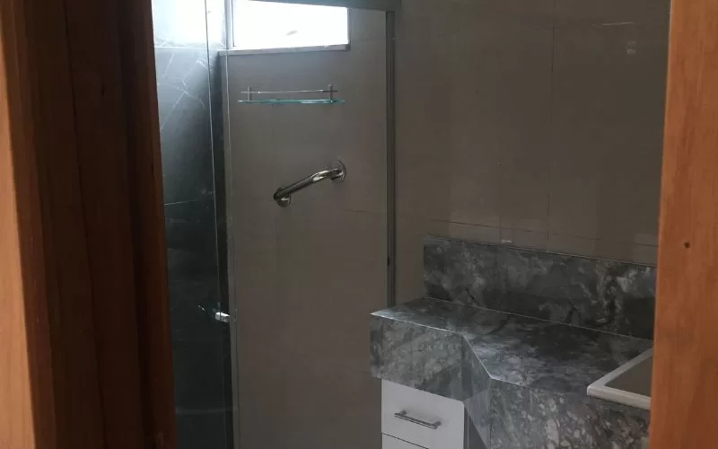 Casa de banho com chuveiro e lavatório em mármore.
