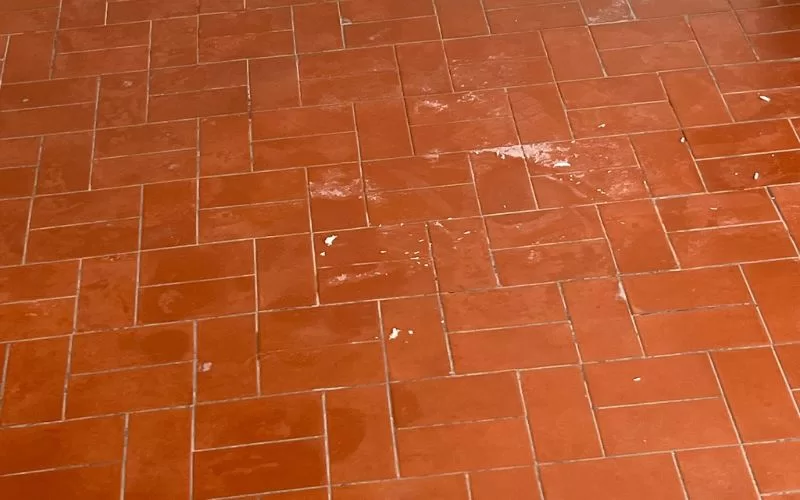 Chão de tijoleira com marcas de desgaste.