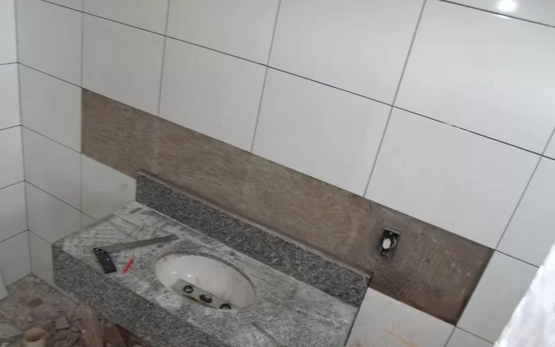 Instalação de lavatório em casa de banho inacabada.