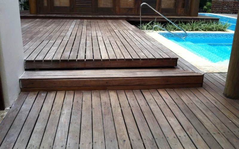 Deck de madeira junto a piscina azul