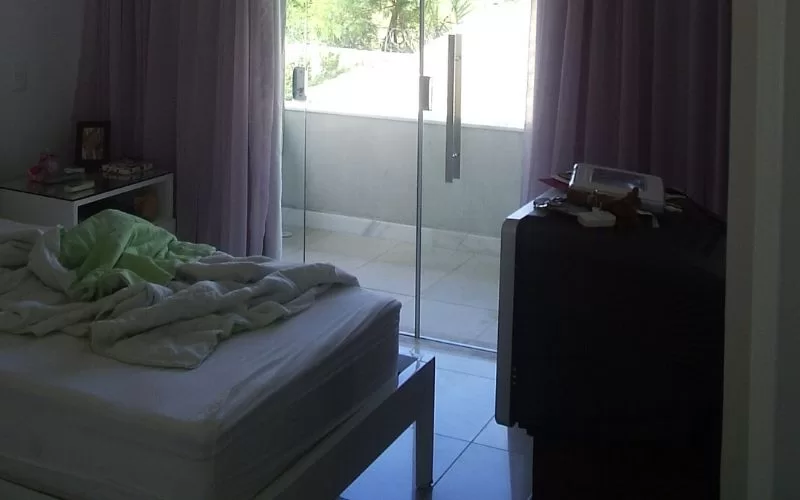 Quarto com cama desarrumada e varanda iluminada.