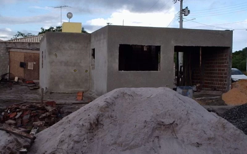 Casa em construção com pilha de areia em frente.