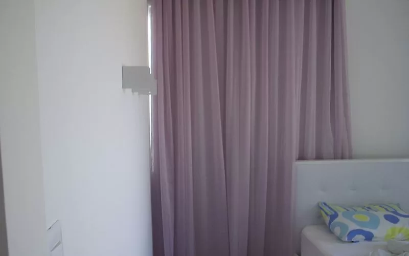 Quarto com cortina lilás e cama branca