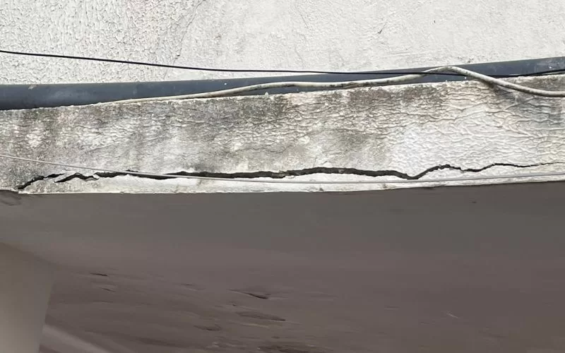 Racha em telhado de concreto com fios elétricos.