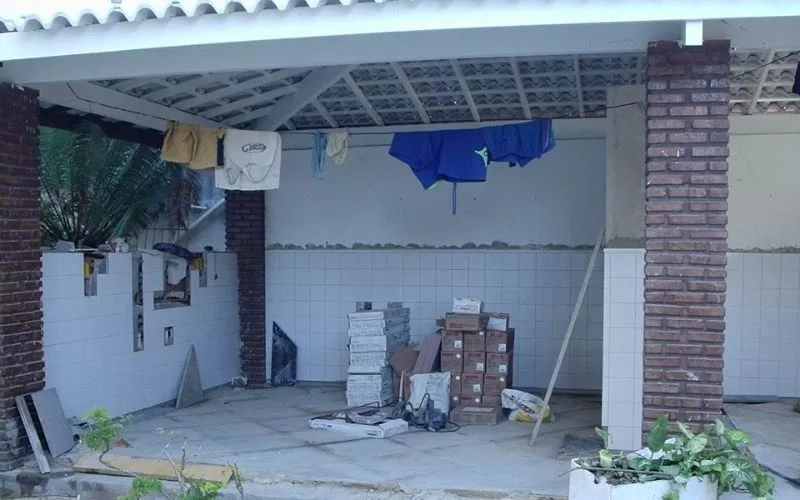 Área de construção com materiais e roupas penduradas.