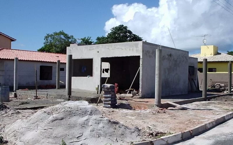 Construção de casa em andamento com estrutura visível.