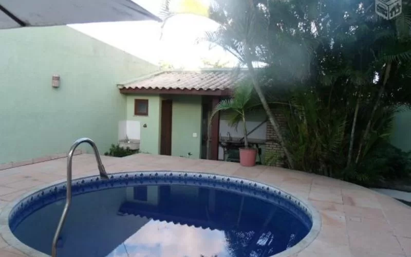 Piscina pequena em pátio com plantas e paredes verdes.