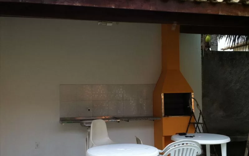 Churrasqueira e mesa em área de lazer ao ar livre.