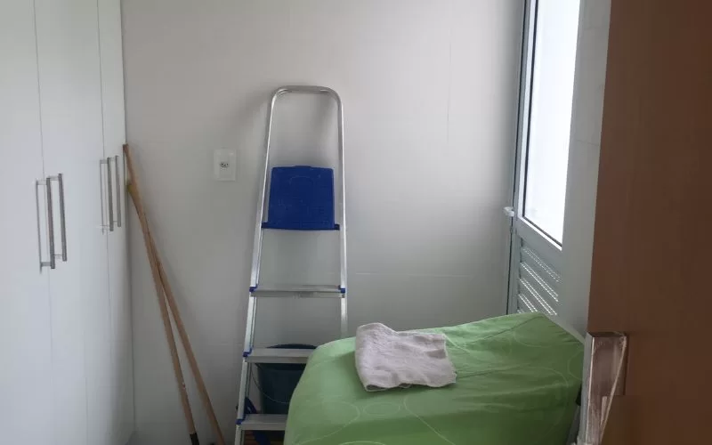 Área de serviço com escada e armário branco.