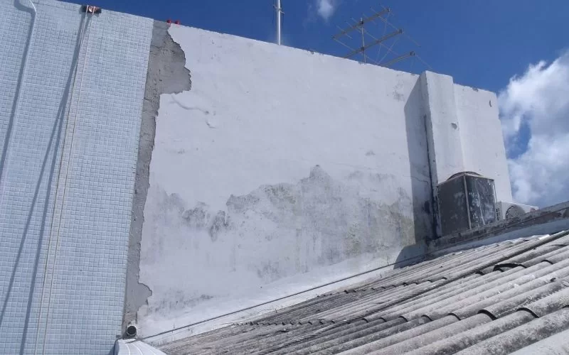 Parede desgastada com antenas no telhado.