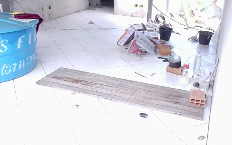 Sala em renovação com chão branco e materiais espalhados.