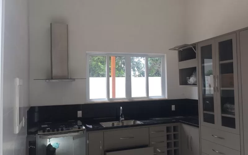 Cozinha moderna com móveis cinza e janelas grandes.