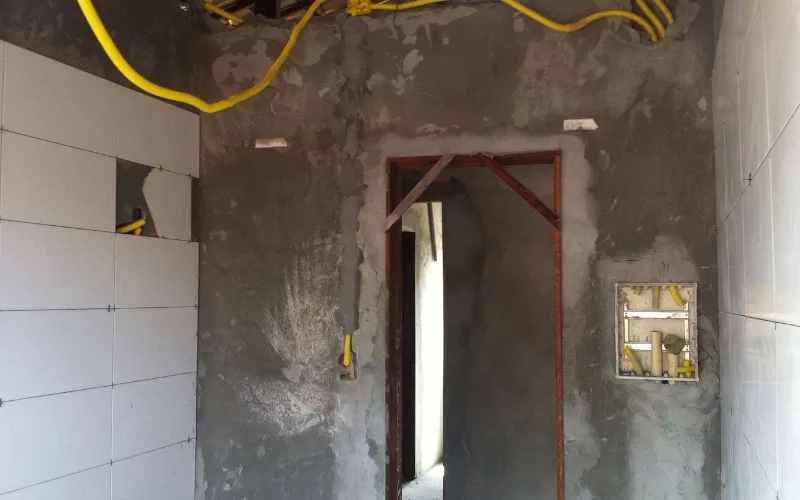 Interior em obras com fios e azulejos expostos.