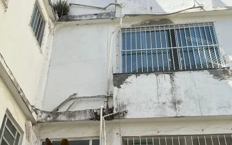 Fachada antiga com janelas gradeadas e pintura desgastada.