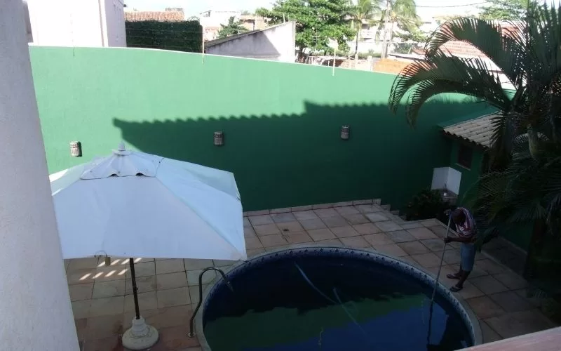 Pátio com piscina, guarda-sol e palmeiras.