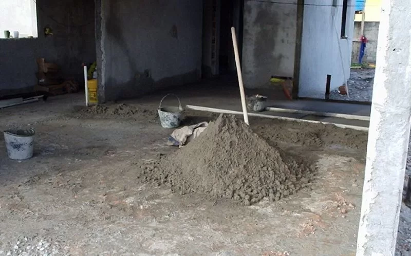 Construção civil com pilha de areia e baldes.