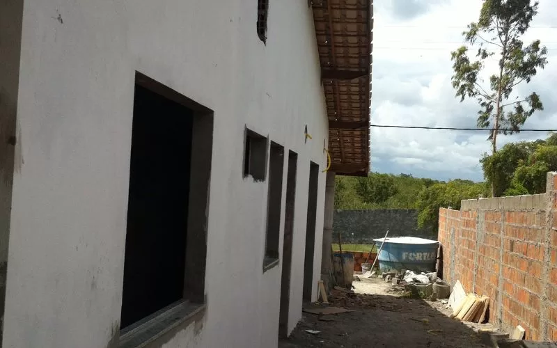 Casa em construção com parede de tijolos à vista.