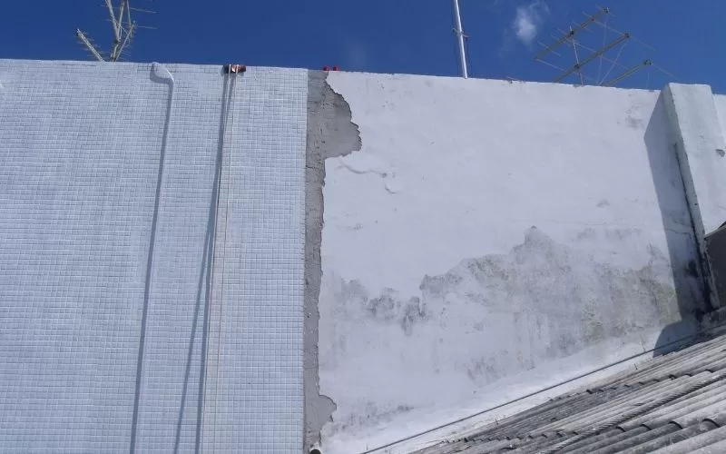 Parede exterior com infiltrações e azulejos.