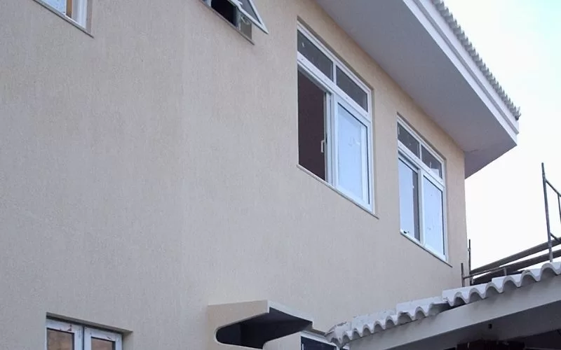 Fachada de casa com janelas grandes e teto branco.