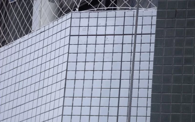 Parede de azulejos brancos e tela metálica.
