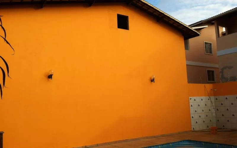 Parede laranja de casa com piscina à frente.