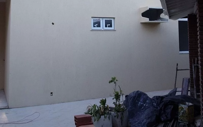 Parede exterior com janela pequena e plantas.