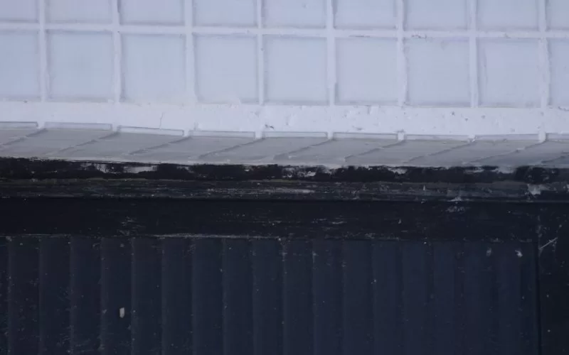 Parede de azulejos brancos e painel preto.