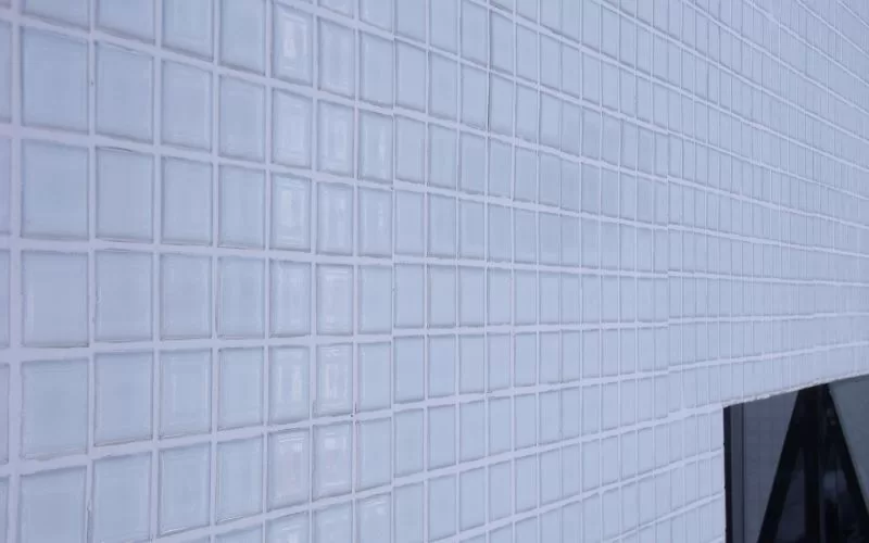Parede de azulejos brancos com reflexo.