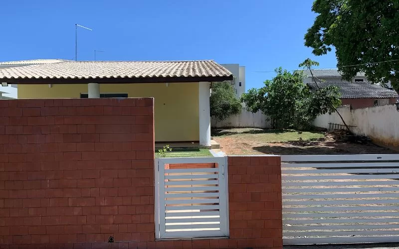 Casa com parede de tijolos e portão branco.